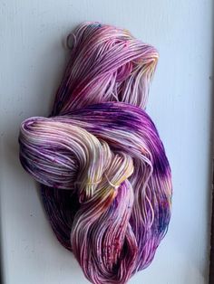 a skein of yarn is hanging on a doorknob with white and purple streaks