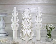 three white vases sitting on top of a table next to each other with flowers in them