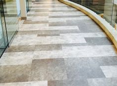 an empty hallway with glass walls and tiled flooring