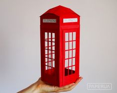 a hand holding up a red phone booth