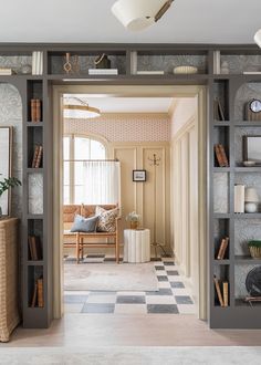 a living room filled with furniture and bookshelves next to a doorway that leads to a sitting area