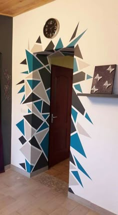 a clock is on the wall next to a door with an artistic design painted on it