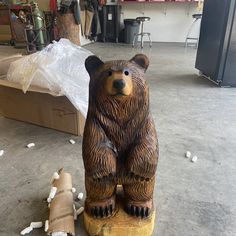 a bear statue sitting on top of a wooden stump next to a piece of wood