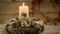 a lit candle sitting on top of a table next to pine cones and other decorations