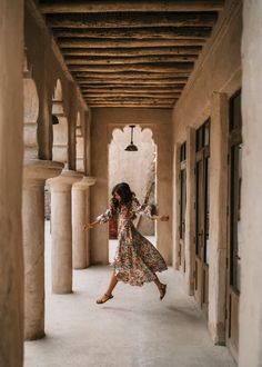 a woman in a long dress is running through an archway