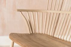 a wooden chair sitting on top of a hard wood floor next to a pink wall