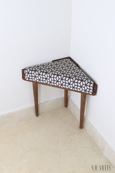 a small wooden table with a black and white pattern on it in the corner of a room