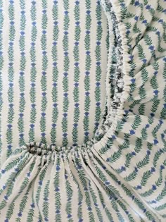 the back of a green and white dress with blue flowers on it's shoulders