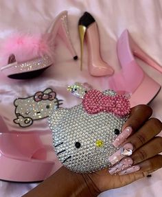 a woman's hand with pink and silver nail polish holding up a hello kitty phone case