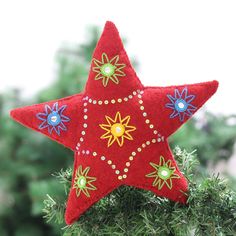 a red star ornament hanging from a christmas tree