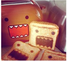 toast with faces drawn on them sitting next to a teapot