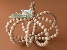 two wooden beaded pumpkins sitting on top of a brown table next to each other