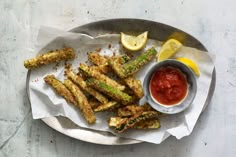 fried asparagus with ketchup and lemon wedges on a silver plate