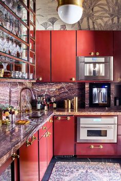 a kitchen with red cabinets and an area rug in front of the stove top oven