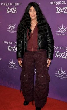 a woman with long black hair standing on a red carpet