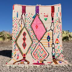 a colorful rug is on the ground in front of some cacti and cactus plants