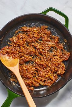 a frying pan filled with fried food and a wooden spoon on top of it