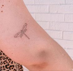 a small dragonfly tattoo on the right arm and shoulder, it appears to be drawn in black ink