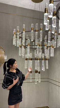 a woman standing in front of a chandelier made out of glass bottle bottles