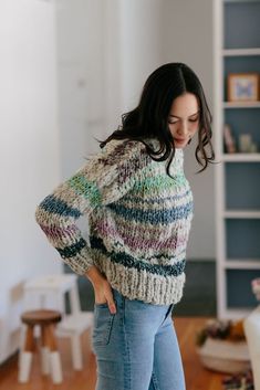 a woman standing in a living room with her hands on her hips and looking down