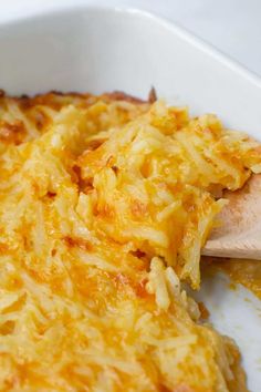 a casserole dish with cheese on top and a wooden spoon in the middle