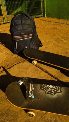 two skateboards and a backpack are sitting on the ground in front of a fence