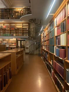 a library filled with lots of books on shelves next to a stair case full of books