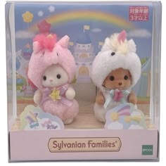 two small stuffed animals are sitting in a box with a rainbow and castle behind them