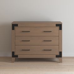 a wooden dresser sitting on top of a hard wood floor next to a white wall