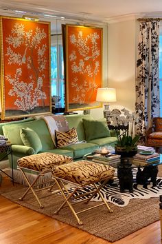 a living room filled with furniture next to a window covered in orange and white curtains