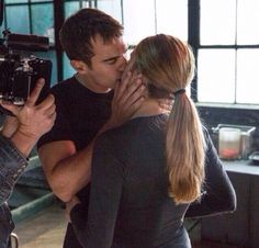 a man and woman are kissing in front of a camera set up for a movie