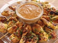 grilled chicken skewers with dipping sauce on a glass platter