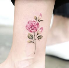 a pink rose tattoo on the ankle with green leaves and buds in it's center