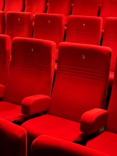 rows of red seats in an auditorium with numbers on the seat back and armrests