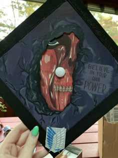 someone is holding up a graduation cap with an image of a creepy face on it