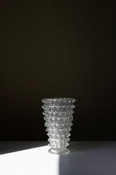 a clear glass vase sitting on top of a white table next to a black wall