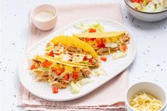 two tacos are sitting on a plate next to a bowl of salad and a cup