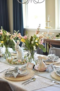 a dining room table set for easter with bunny figurines and flowers in vases