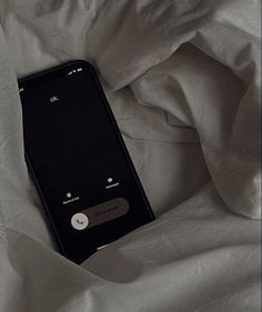 an iphone sitting on top of a bed covered in white sheets