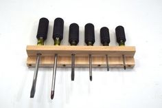 six screwdrivers are mounted on a wooden rack