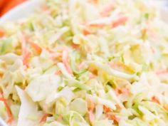 a bowl filled with coleslaw and carrots on top of a table