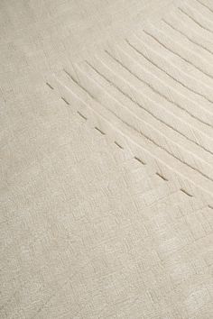 a person walking across a sandy beach next to a wave pattern in the sand on a sunny day