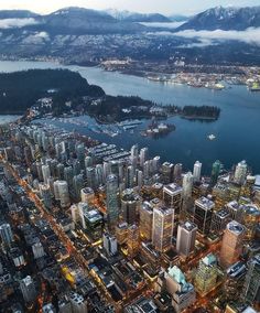 an aerial view of a city at night with mountains in the background and water below