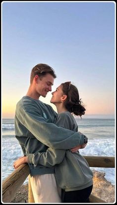 a man and woman standing next to each other near the ocean