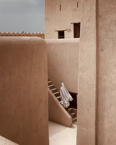 an adobe building with stairs leading up to the upper floor and another room on the second floor