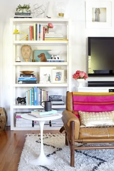 a living room filled with furniture and a flat screen tv on top of a book shelf