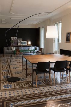 a living room with a large wooden table surrounded by black chairs and rug on the floor