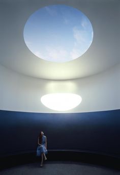 a woman sitting on the floor in front of a round window with a skylight