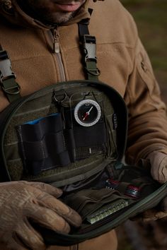 a man in brown jacket holding a green bag filled with tools and gadgets