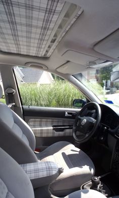 the interior of a car with grey and white seats, steering wheel and dash board